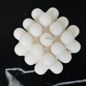 Black and white overhead view of wax candle with symmetrical ornament and wick in center on table in house